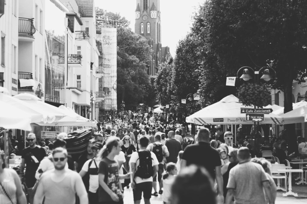 A black and white photo capturing a busy street filled with people in Sopot, Poland during the day.