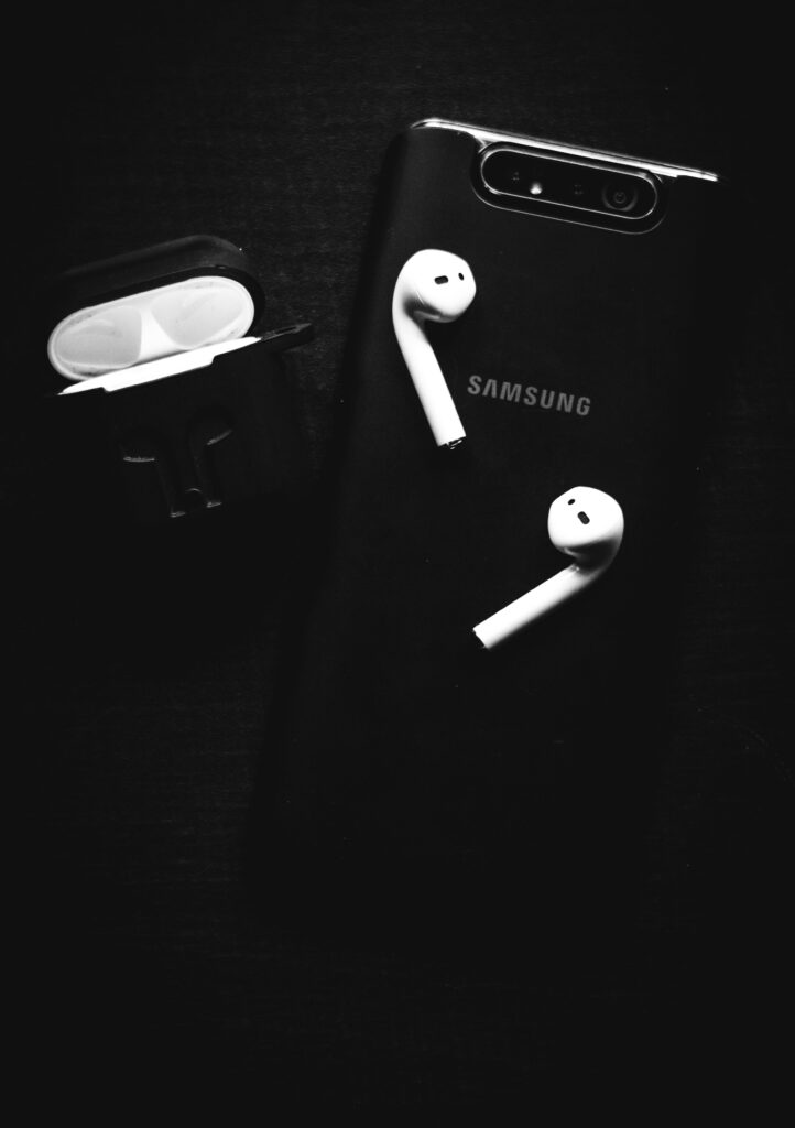 Black and white image of Samsung smartphone with wireless earbuds, emphasizing technology essentials.